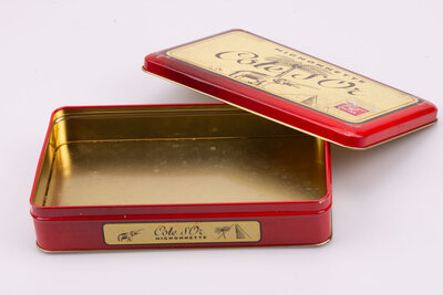 Ancienne boite en métal avec des teintes rouges et jaunes de la marque de chocolat Côte d'or