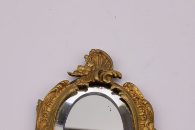 Miroir face à main en bronze, fin 19ème- début 20ème,  au décor de vagues, feuilles d’acanthe et fleurs. Traces du temps : miroir piqué. 