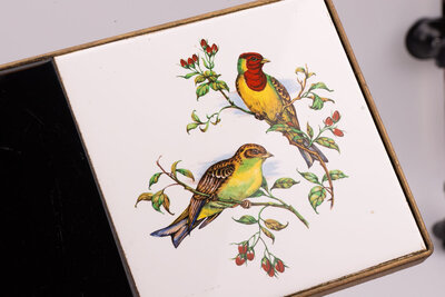 Porte-journaux en fer forgé doré avec tablettes en faïence et dessins d'oiseaux posés sur la partie supérieure de l'objet