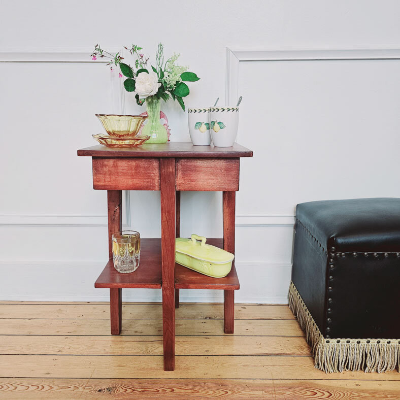 Meuble d'appoint en bois avec plusieurs étages et divers objets vintages sur des tonalités jaunes