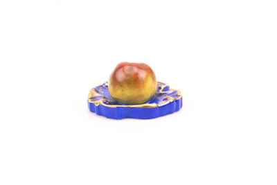 Ancien presse-papier en porcelaine représentant une pomme posée sur un socle/plateau.