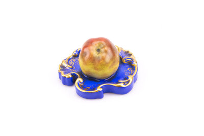 Ancien presse-papier en porcelaine représentant une pomme posée sur un socle/plateau.