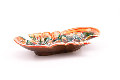 Un grand plat en céramique signé "Vallauris". Il est dans les tons orangés et brun réhaussé par des mélanges de vert et de blanc.