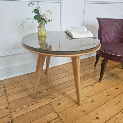 Table basse en bois clair massif dans un design très épuré.  De style scandinave, les pieds sont en bois très clair.  Le plateau de la table est fait de bois plus foncé et est travaillé avec les lignes dans le bois. Il est surmonté d'une plaque en verre épaisse.