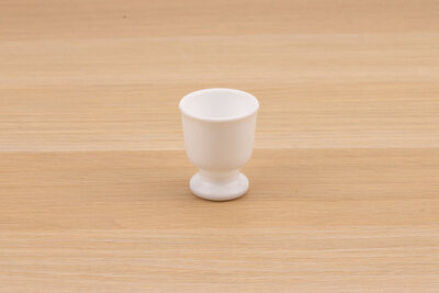 Coquetier vintage en opaline blanc sur un fond en bois de chez Seca