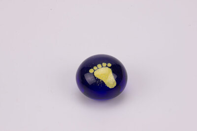Boule de sulfure en verre, représentant  un pied jaune sur un fond bleu uni. 