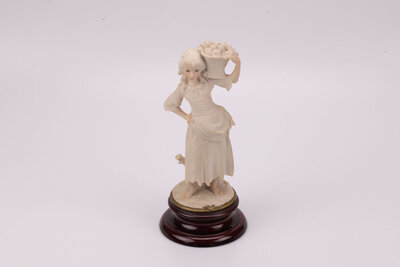 Jeune paysanne avec son panier de fruits en porcelaine et un socle en bois. Cette figurine de Giuseppe Armani date des années 80