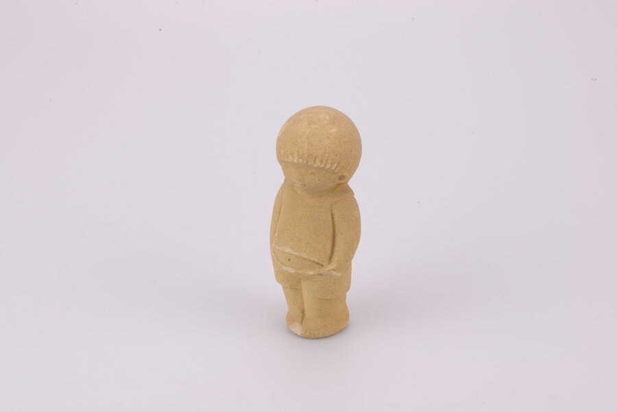 Figurine en grès d'un petit garçon debout les mains dans les poches. 