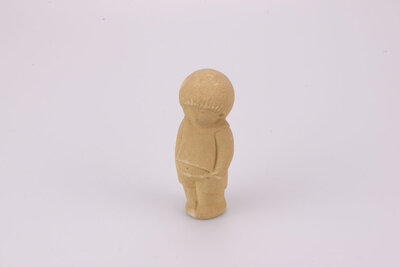Figurine en grès d'un petit garçon debout les mains dans les poches. 