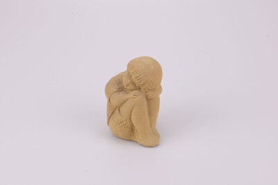Figurine en grès d'un petit garçon dormant assis et recroquevillé sur ses genoux les bras dans le dos