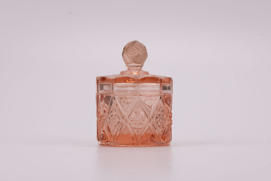 Délicat pot rose en verre avec son couvercle avec un léger éclat sur le dessus