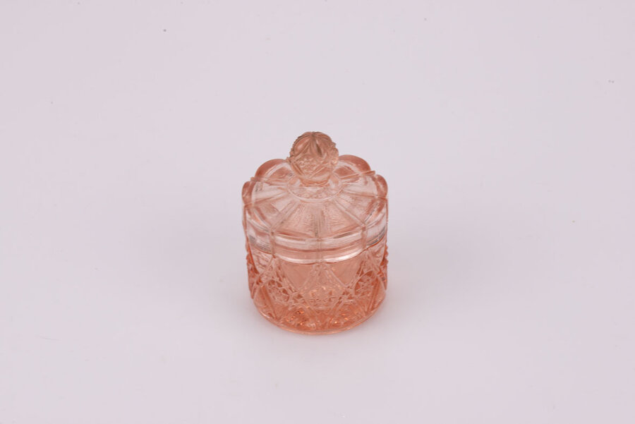 Délicat pot rose en verre avec son couvercle avec un léger éclat sur le dessus