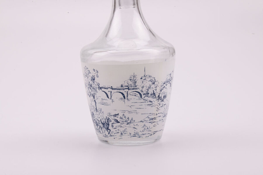 Service à liqueur en cristal d'Arques avec 1 bouteille et 6 petits verres dans leur boite d'origine. Sur chacun des objets, il y a des dessins bleus, rouges, verts ou bruns représentant un paysage