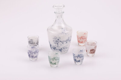 Service à liqueur en cristal d'Arques avec 1 bouteille et 6 petits verres dans leur boite d'origine. Sur chacun des objets, il y a des dessins bleus, rouges, verts ou bruns représentant un paysage