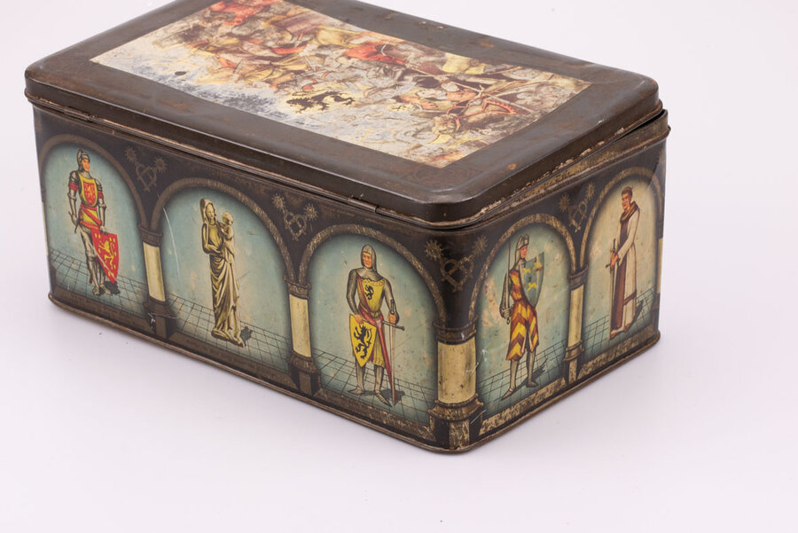 Ancienne boite en métal avec des dessins avec plein de chevaliers médiévaux avec des touches de bleu, blanc et de métal avec un texte écrit en néerlandais