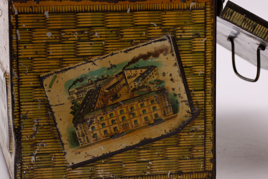 Ancienne boite en métal avec des peintures de panier en osier qui paradoxalement donne impression de coffre-fort avec des teintes dorées-brunes de la marque belge de chocolat Senez-Sturbelle