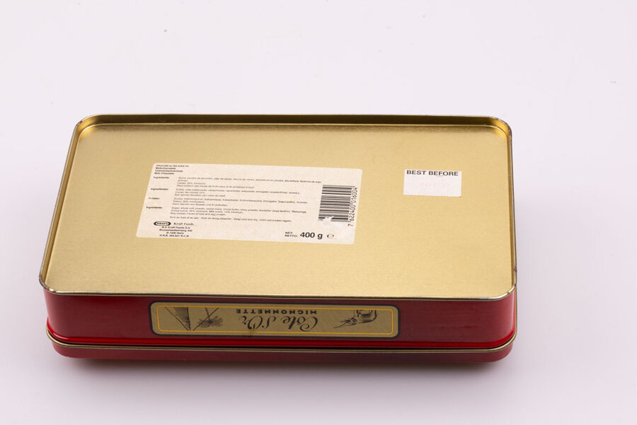 Ancienne boite en métal avec des teintes rouges et jaunes de la marque de chocolat Côte d'or