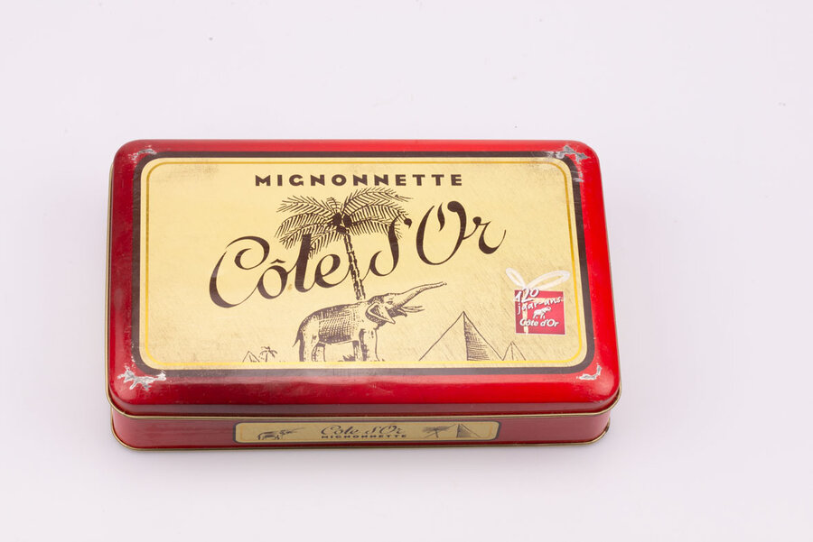 Ancienne boite en métal avec des teintes rouges et jaunes de la marque de chocolat Côte d'or