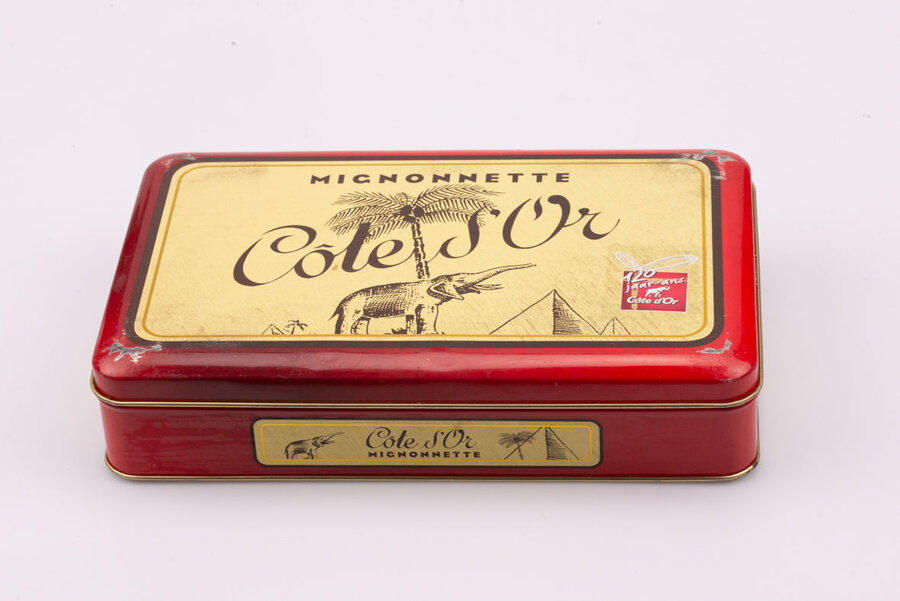 Ancienne boite en métal avec des teintes rouges et jaunes de la marque de chocolat Côte d'or