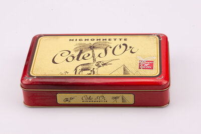 Ancienne boite en métal avec des teintes rouges et jaunes de la marque de chocolat Côte d'or