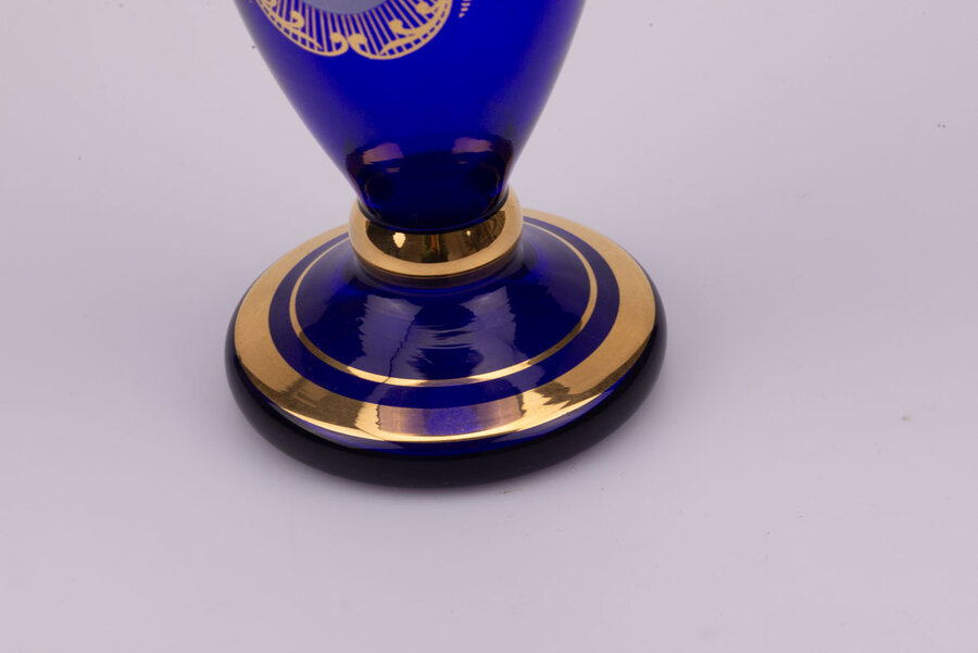 Vase en cristal bleu dans un style bohème avec des motifs de fleurs et plusieurs liserés dorés qui structurent l'objet