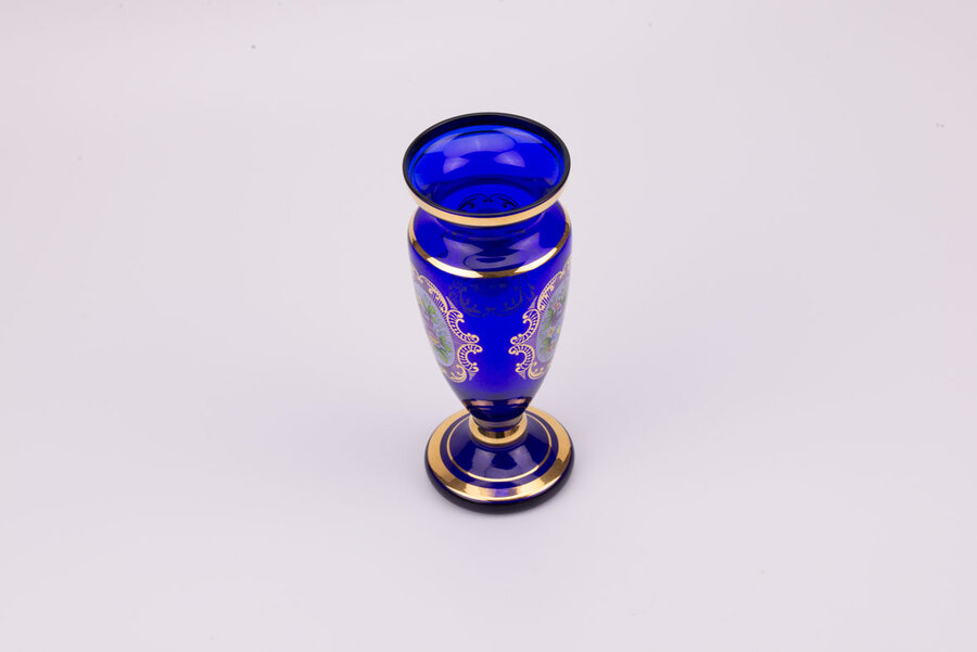 Vase en cristal bleu dans un style bohème avec des motifs de fleurs et plusieurs liserés dorés qui structurent l'objet