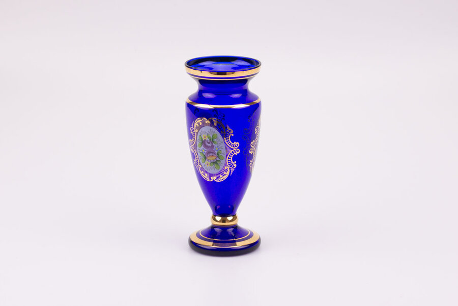 Vase en cristal bleu dans un style bohème avec des motifs de fleurs et plusieurs liserés dorés qui structurent l'objet