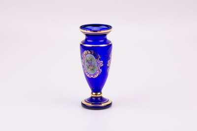 Vase en cristal bleu dans un style bohème avec des motifs de fleurs et plusieurs liserés dorés qui structurent l'objet