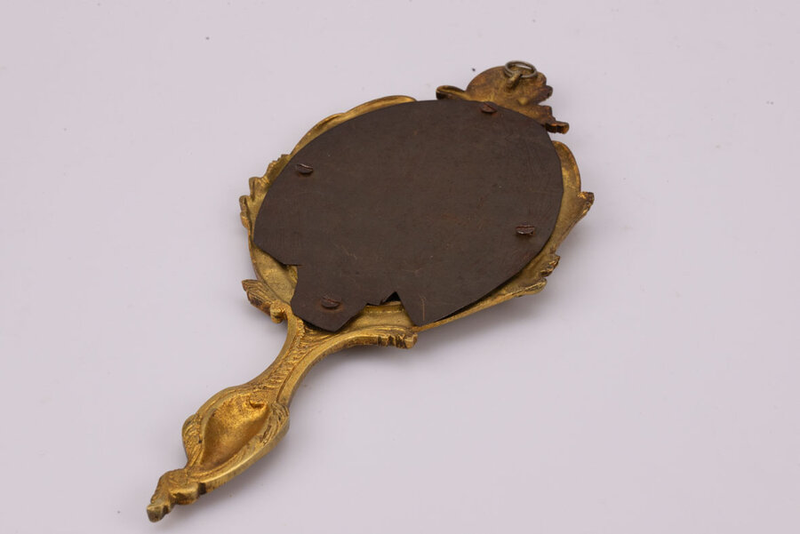 Miroir face à main en bronze, fin 19ème- début 20ème,  au décor de vagues, feuilles d’acanthe et fleurs. Traces du temps : miroir piqué. 