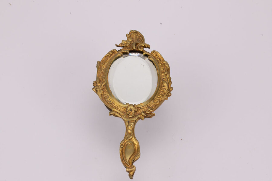 Miroir face à main en bronze, fin 19ème- début 20ème,  au décor de vagues, feuilles d’acanthe et fleurs. Traces du temps : miroir piqué. 