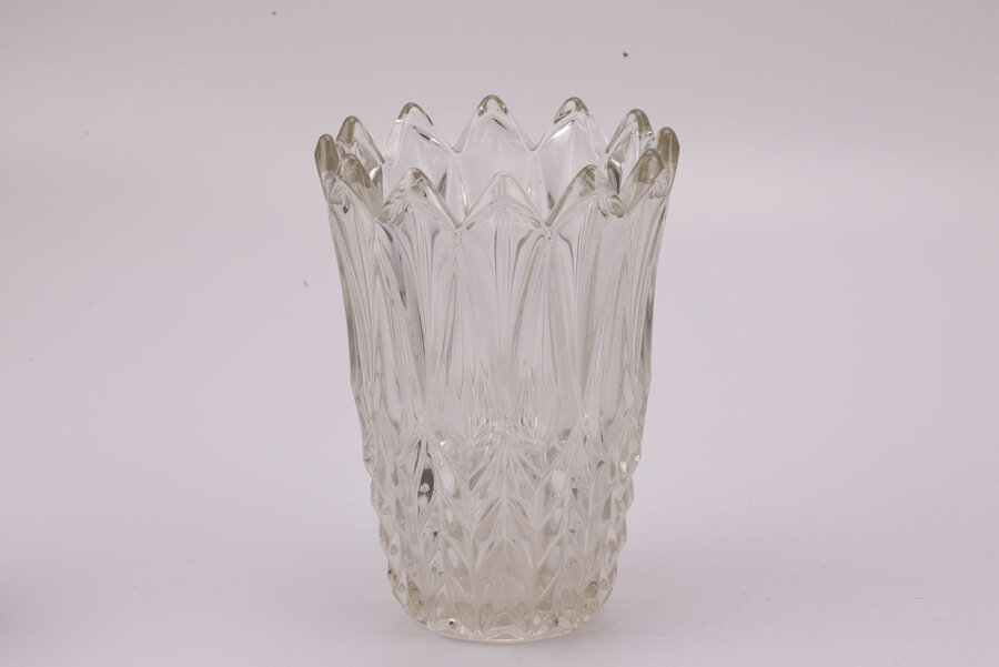 Imposant vase en verre avec son extrémité supérieur en forme de couronne et l'entièreté de l'objet est sculptée avec des formes triangulaires.