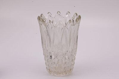 Imposant vase en verre avec son extrémité supérieur en forme de couronne et l'entièreté de l'objet est sculptée avec des formes triangulaires.